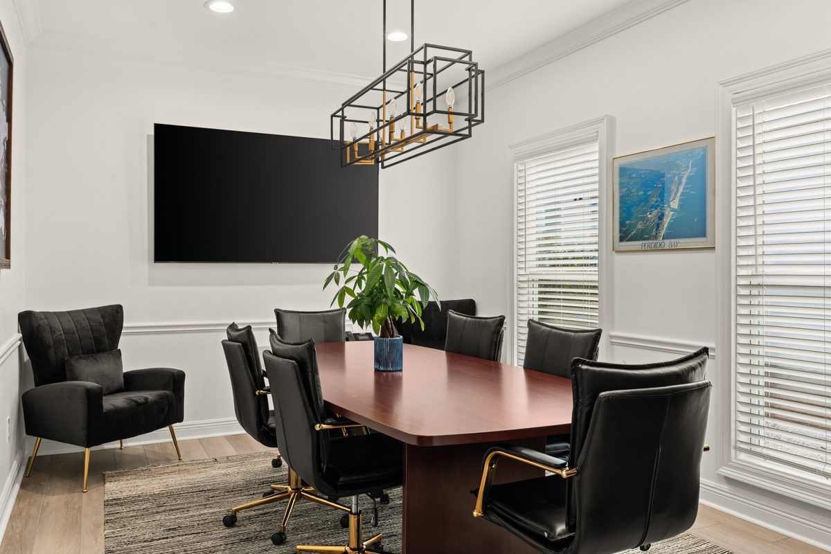 Conference room with a mahogany table, black leather chairs on gold bases, and a black-and-gold cage chandelier — photo by Jimmy Warr