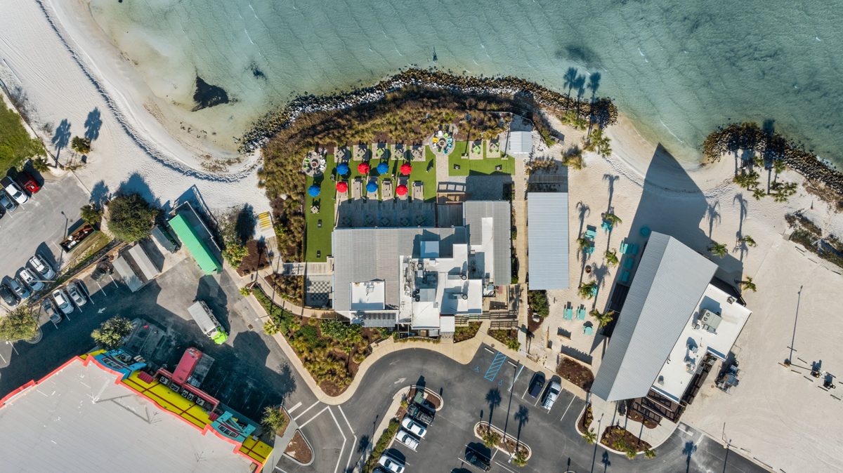 Wider overhead of the restaurant, beach, and turquoise water of Santa Rosa Sound — photo by Jimmy Warr