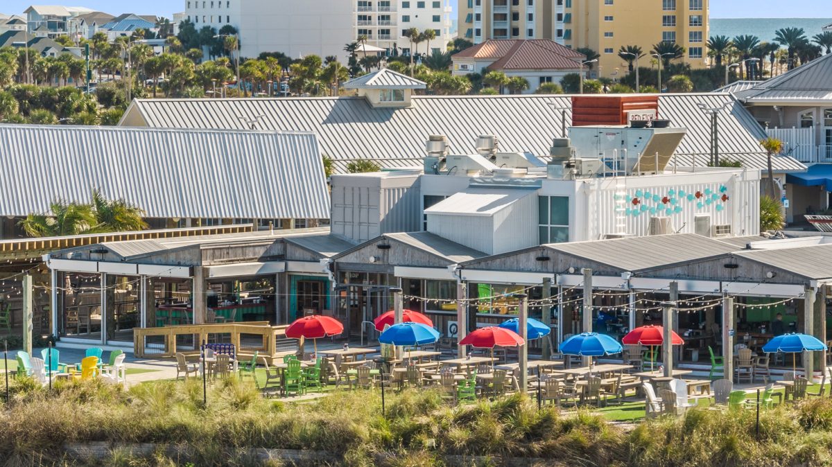 Red and blue umbrellas over the patio tables and open-air dining rooms under string lights — photo by Jimmy Warr