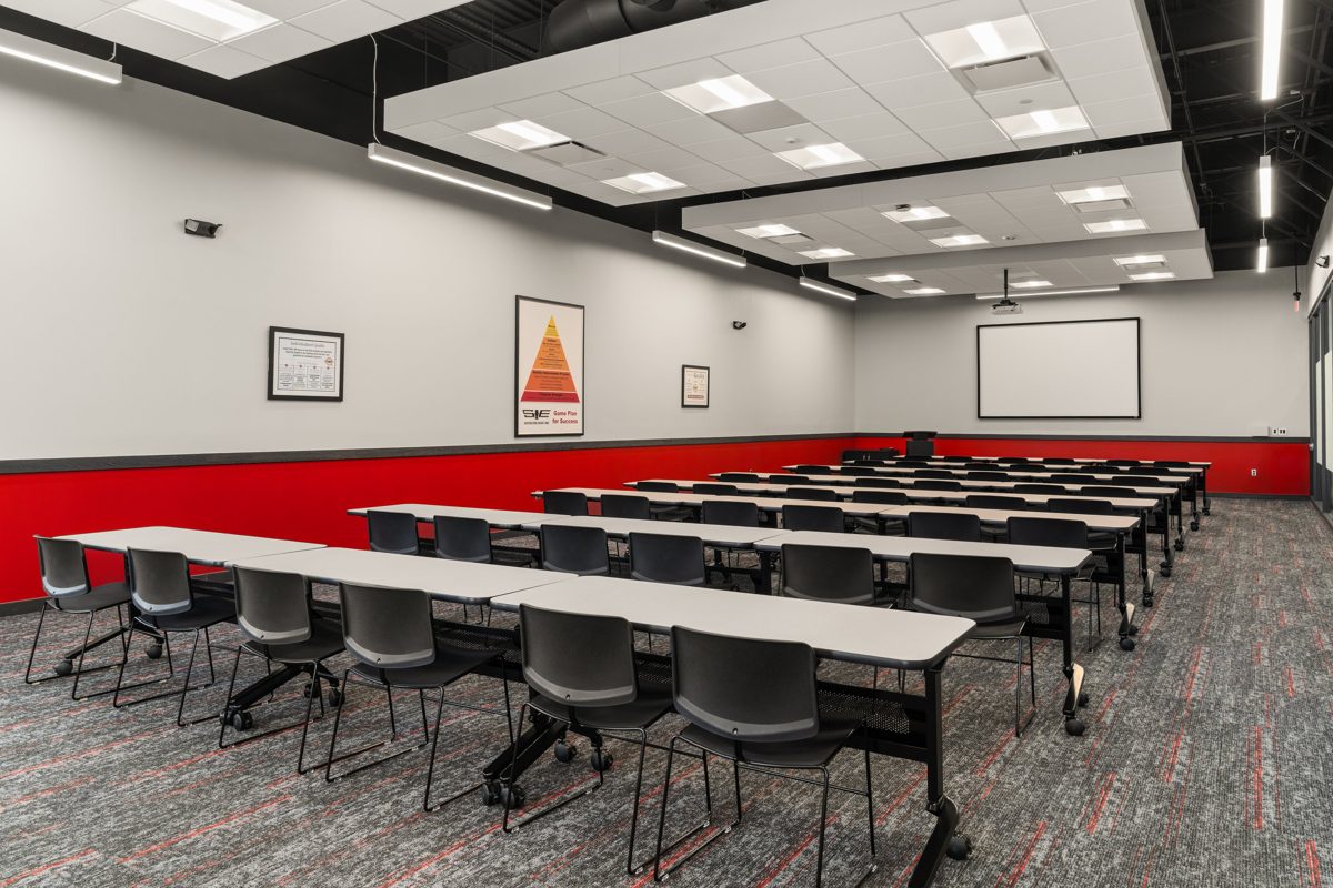 Training room with rows of tables over red-flecked carpet and a red wainscot — photo by Jimmy Warr