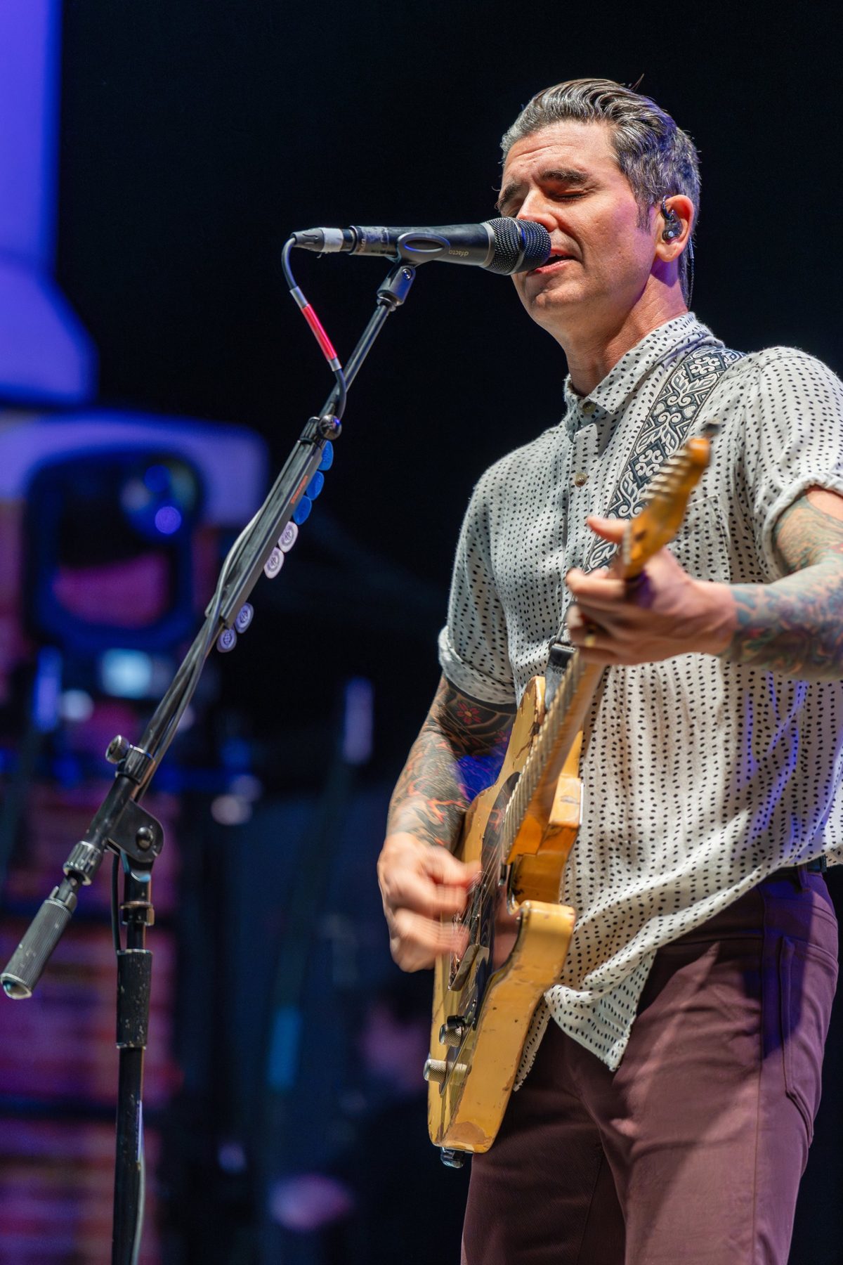 Dashboard Confessional frontman sings eyes-closed into the mic under violet stage light — photo by Jimmy Warr