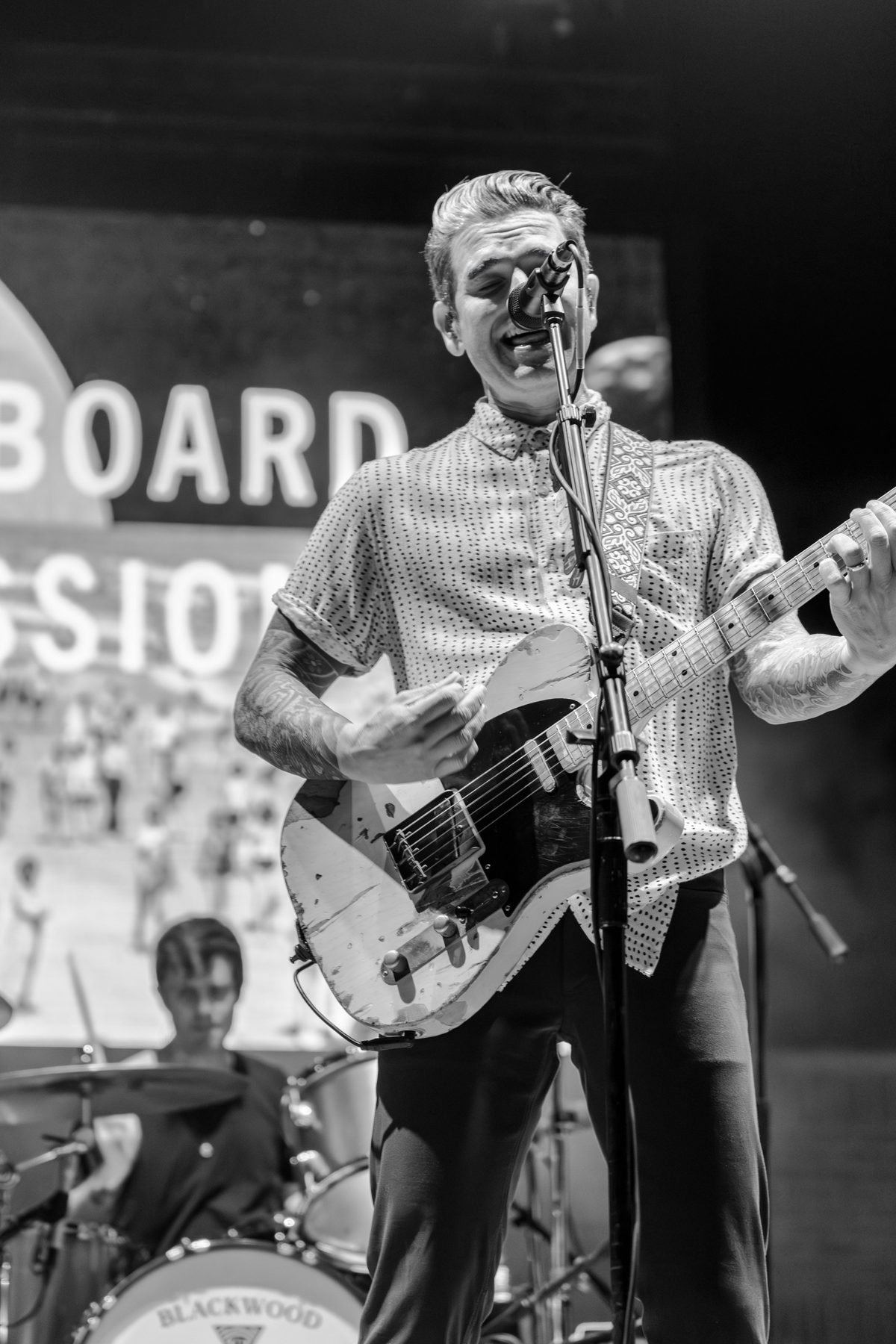 Black-and-white frame of the Dashboard Confessional frontman laughing into the mic, drummer behind — photo by Jimmy Warr