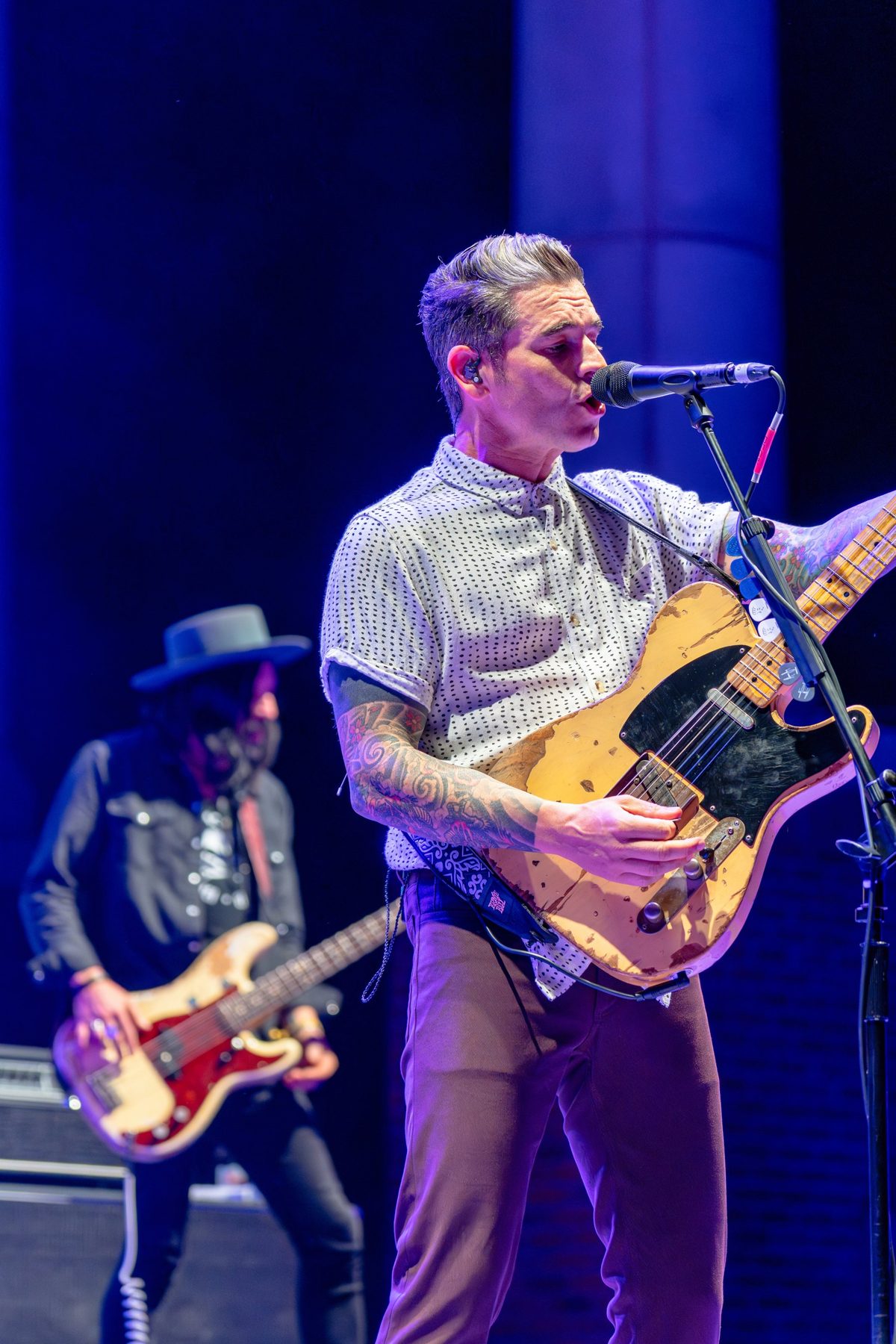 Dashboard Confessional frontman sings under blue light as the bassist plays in a wide-brimmed hat — photo by Jimmy Warr