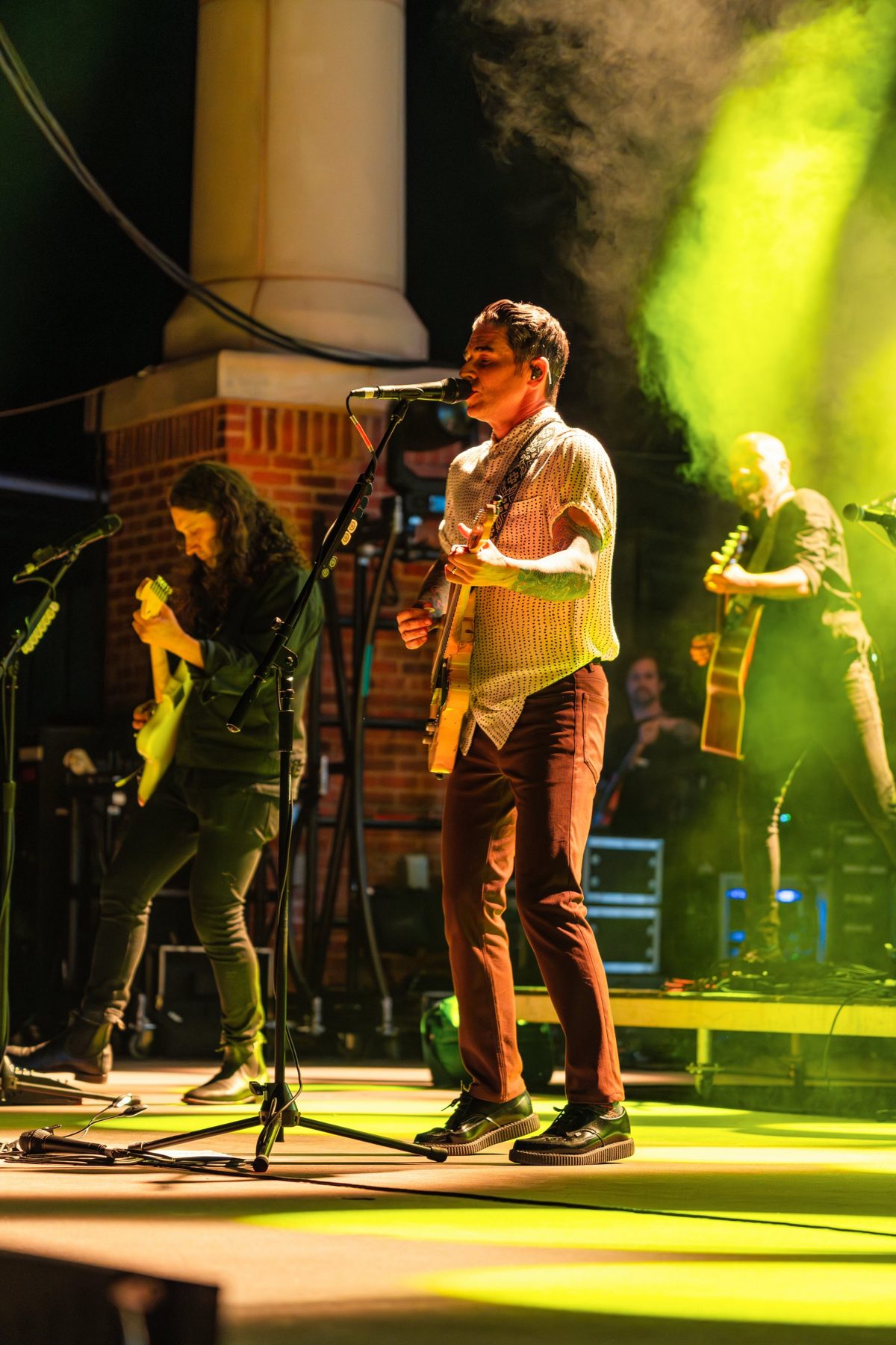 Dashboard Confessional on the Hunter Amphitheater stage, brick columns and green-lit haze behind — photo by Jimmy Warr