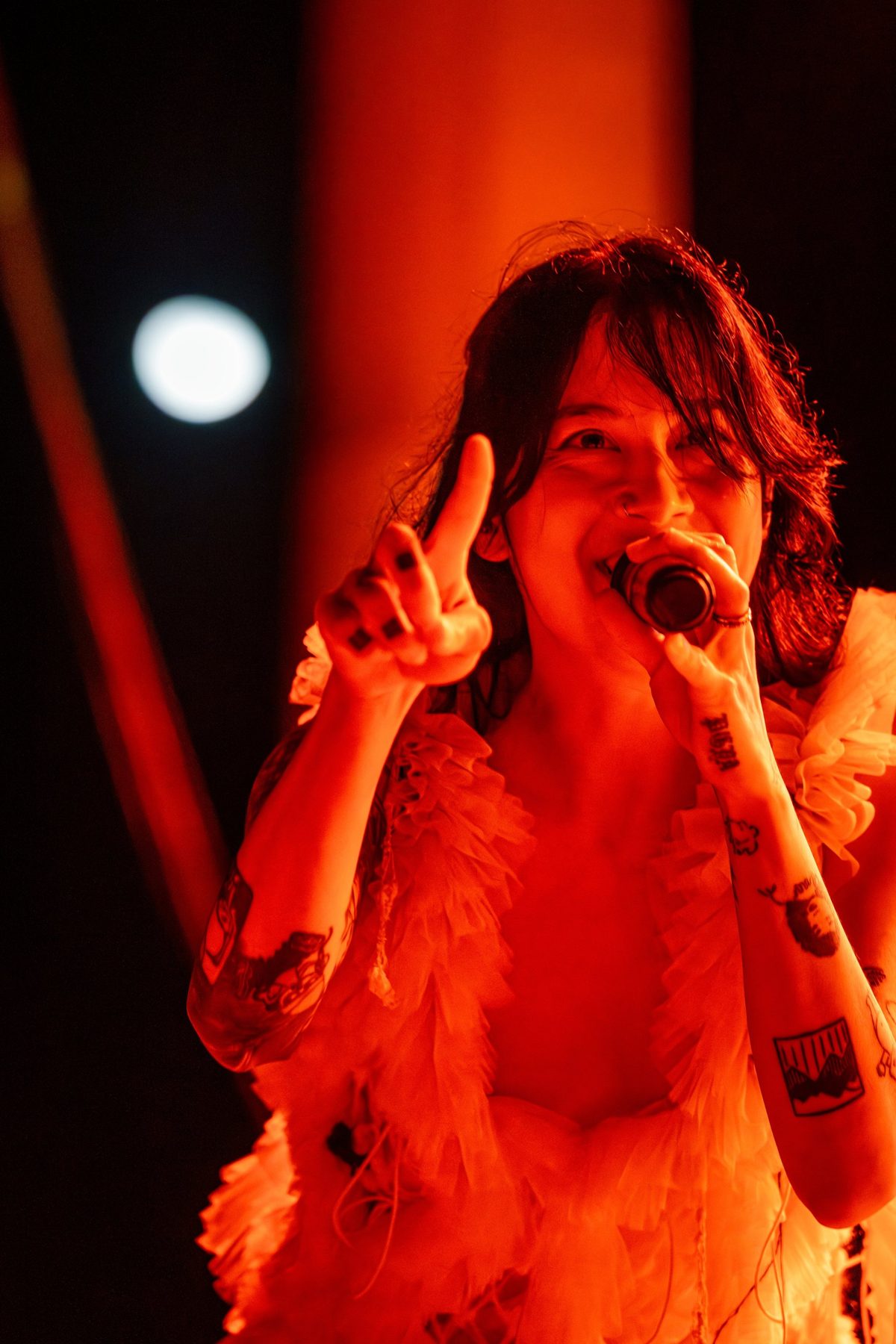 Japanese Breakfast frontwoman points to the crowd in deep red light — photo by Jimmy Warr