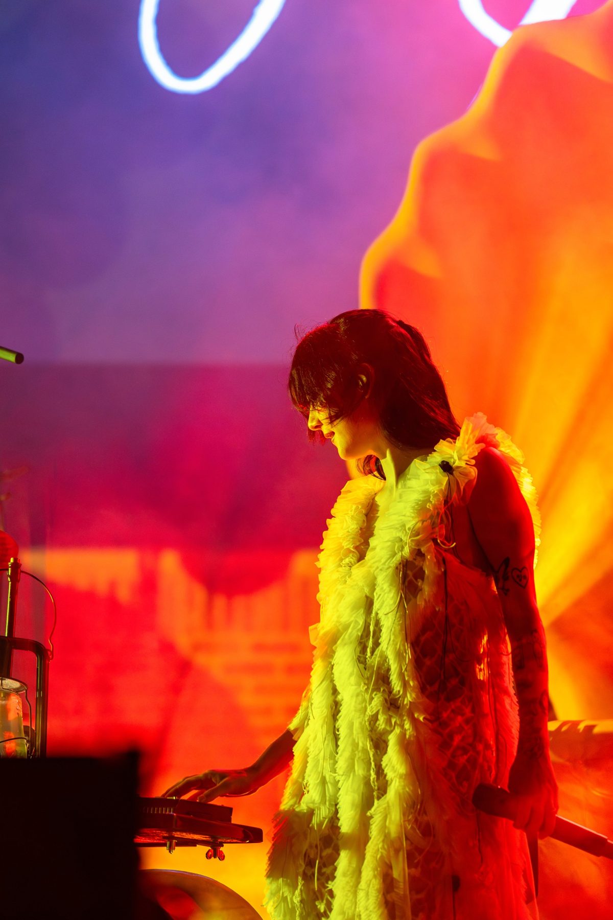 Japanese Breakfast frontwoman in a white ruffled dress against a violet and orange backdrop — photo by Jimmy Warr