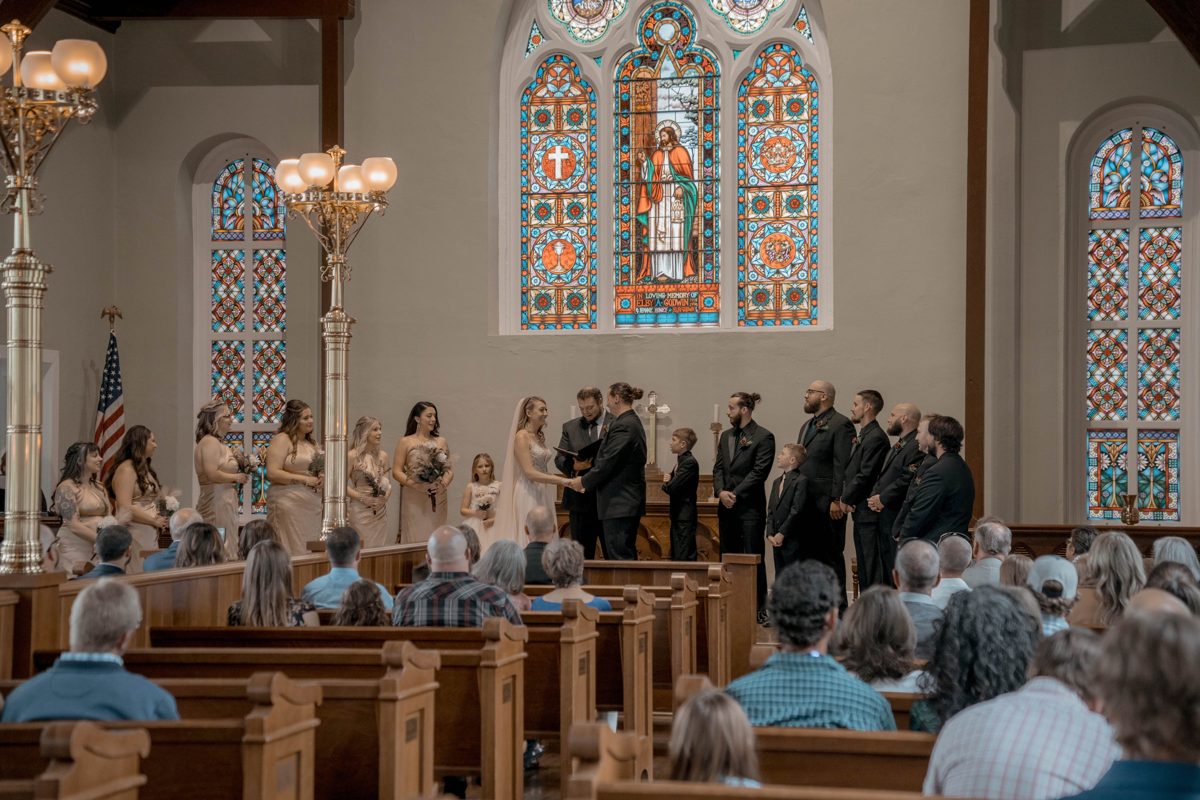 The full ceremony inside Old Christ Church: wedding party lined up beneath the stained glass, guests in the pews — photo by Jimmy Warr