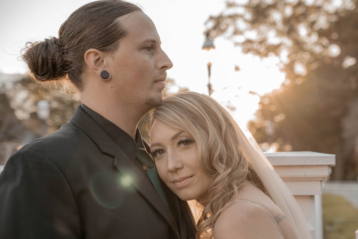 Backlit portrait of the couple at golden hour, the bride leaning into the groom's shoulder — photo by Jimmy Warr
