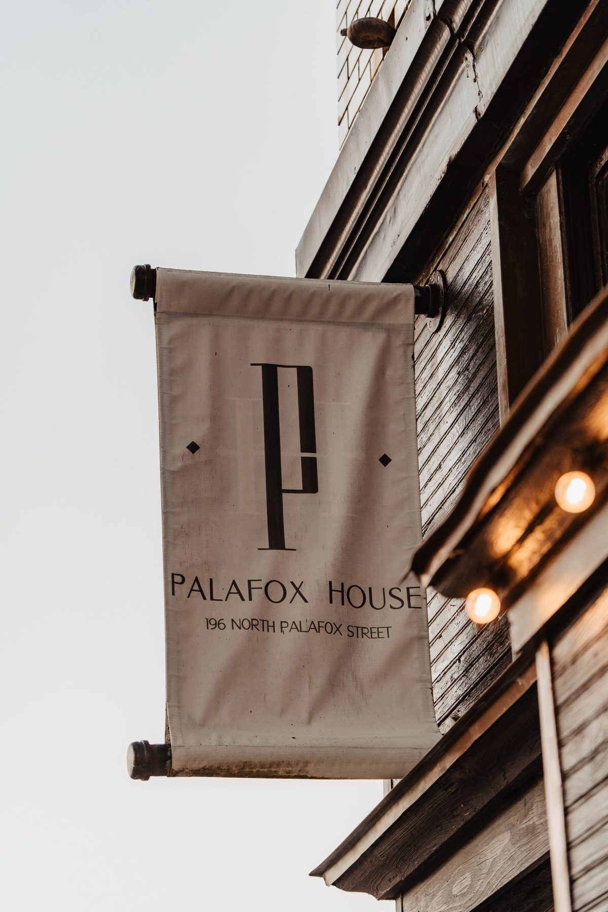 The Palafox House banner on North Palafox Street, string lights glowing beneath it — photo by Jimmy Warr