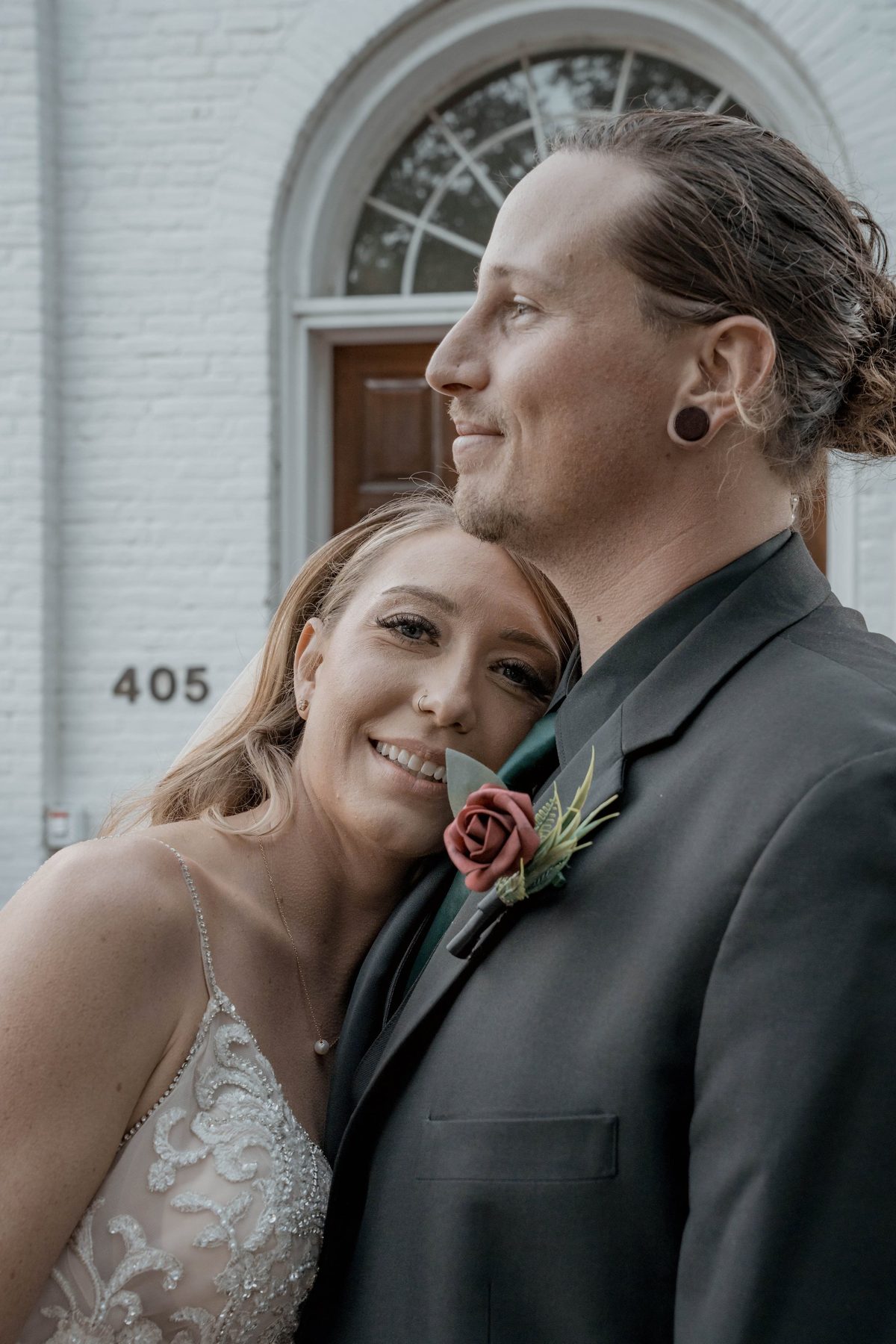The bride rests her head on the groom's shoulder beside the church's 405 address and arched doorway — photo by Jimmy Warr
