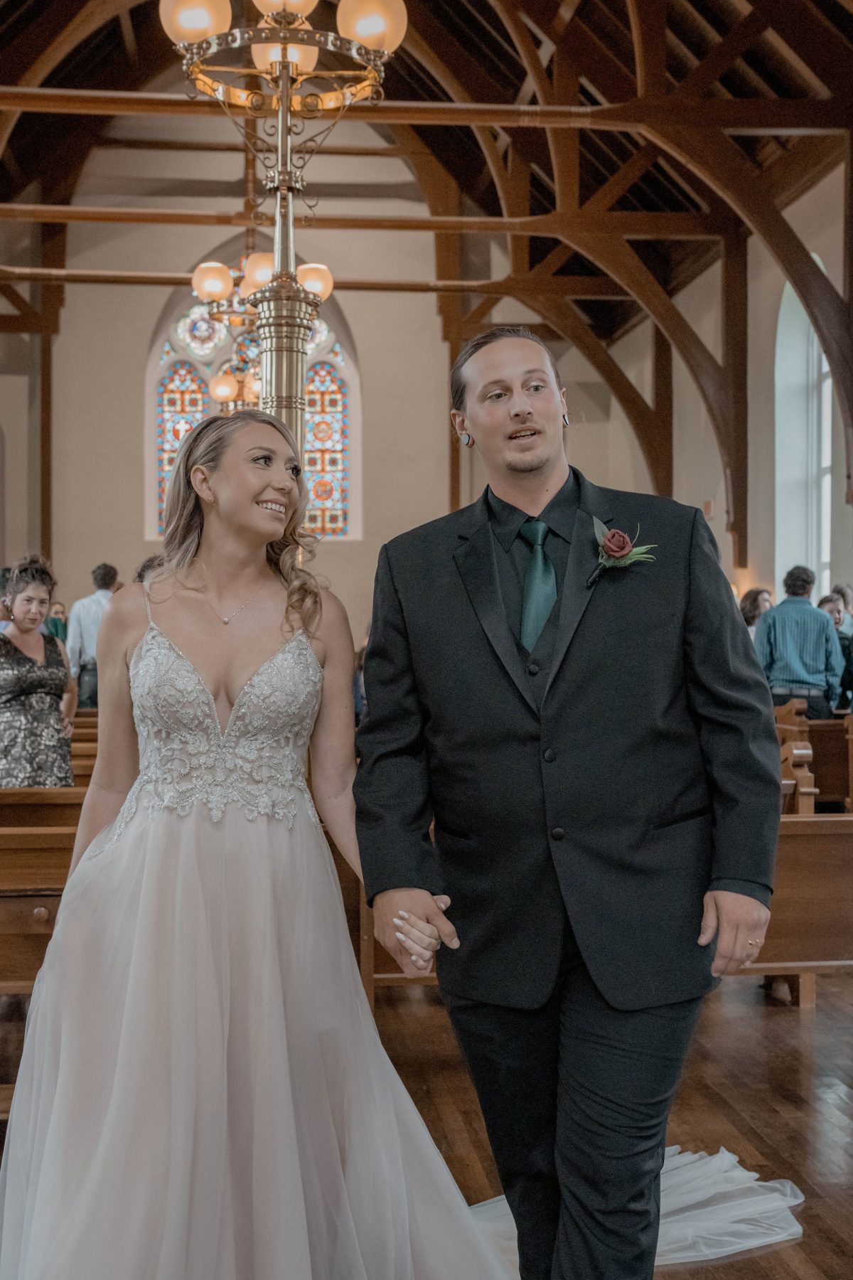 The newlyweds walk back up the aisle under the church's brass chandeliers and timber trusses — photo by Jimmy Warr