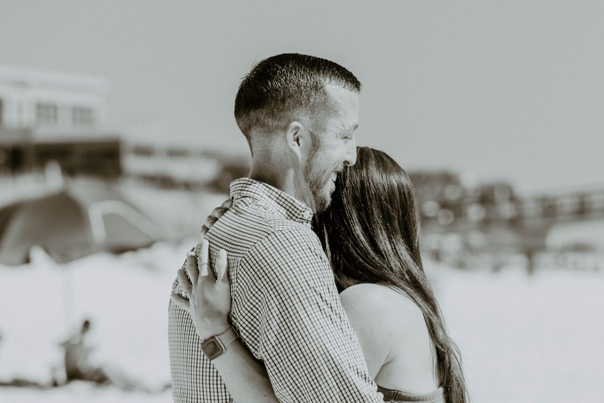 The couple embrace, his face creased in a smile, her ring hand on his back — photo by Jimmy Warr