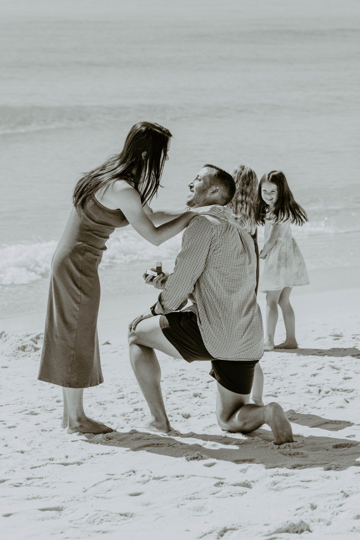 She leans down to him as he kneels, a child grinning over his shoulder — photo by Jimmy Warr