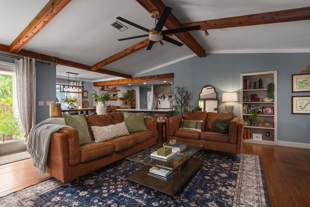 Living room looking back toward the dining room and kitchen under exposed cedar beams — photo by Jimmy Warr