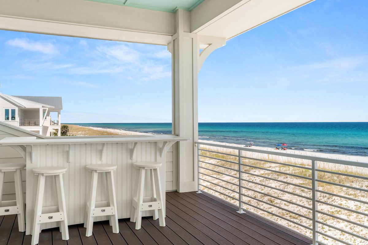 Covered deck bar with white stools looking out over the dunes and the turquoise Gulf at Pensacola Beach — photo by Jimmy Warr