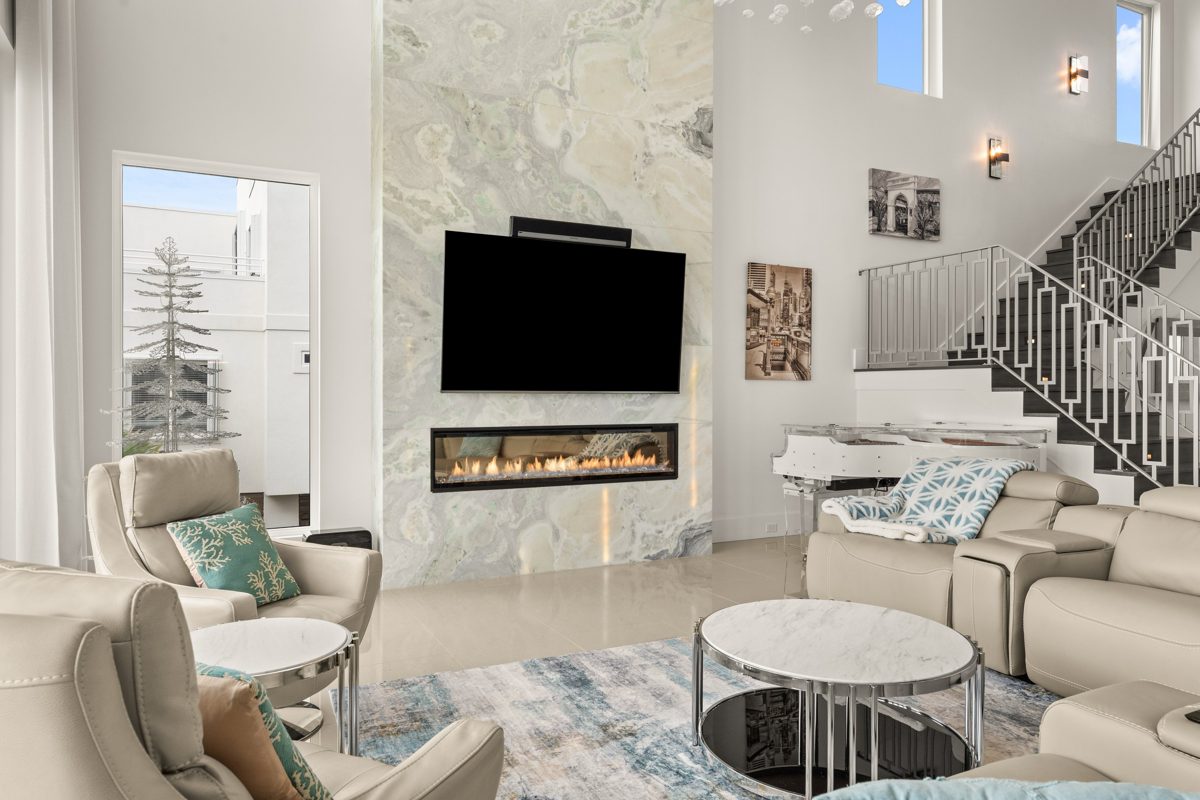 Linear gas fireplace set into a full-height slab of green-veined onyx, cream leather seating and marble side tables in front — photo by Jimmy Warr