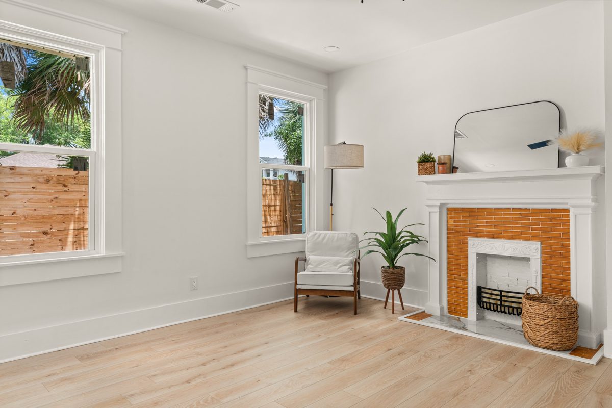 Sunlit room with a white mantel around amber tile and a reading chair between two windows — photo by Jimmy Warr