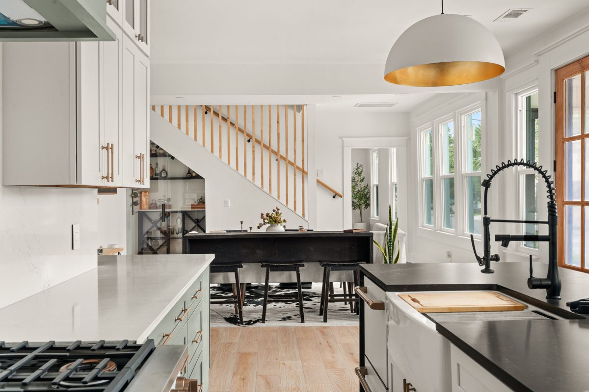 View from the kitchen past the farmhouse sink to the dining table and a slatted wood staircase — photo by Jimmy Warr